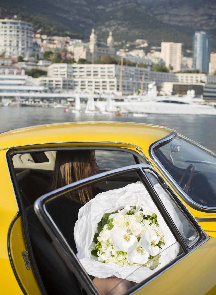 Une jolie jeune femme dans une voiture de prestige tenant un bouquet somptueux