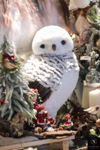 Une chouette entourée de petits sapins et boules de Noël