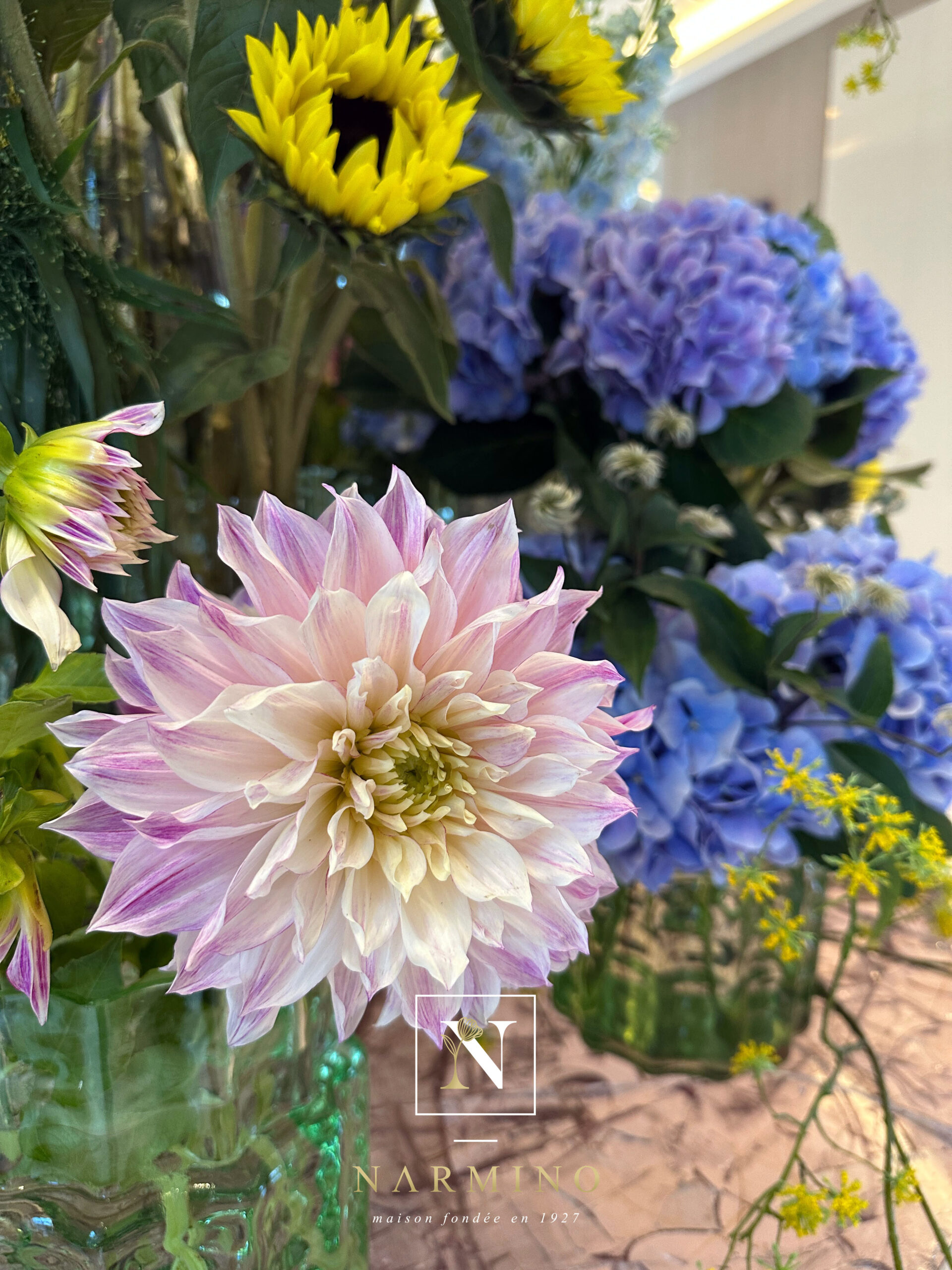 Close-up of a pink dahlia, mauve hydrangeas and sunflowers in a Narmino floral installation